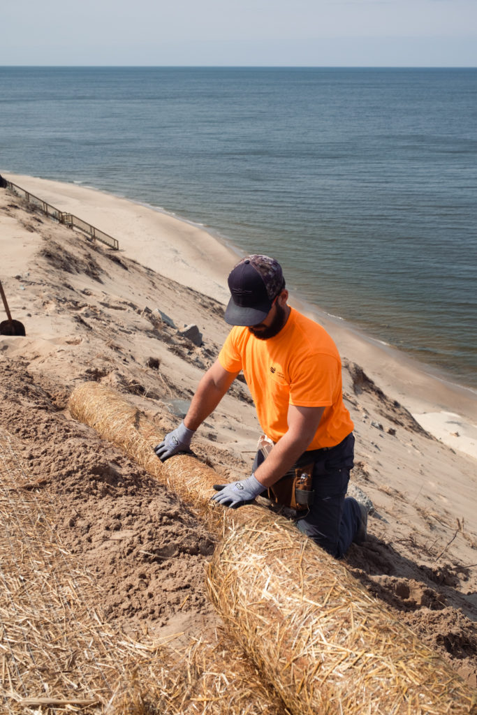 Worker positioning straw mat in sand docket