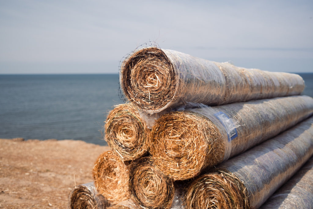 Stacked rolls of straw mats with lake in background