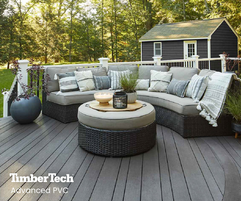 A finished, gray Advanced PVC deck with a multi-width board design and black and gray outdoor furniture.