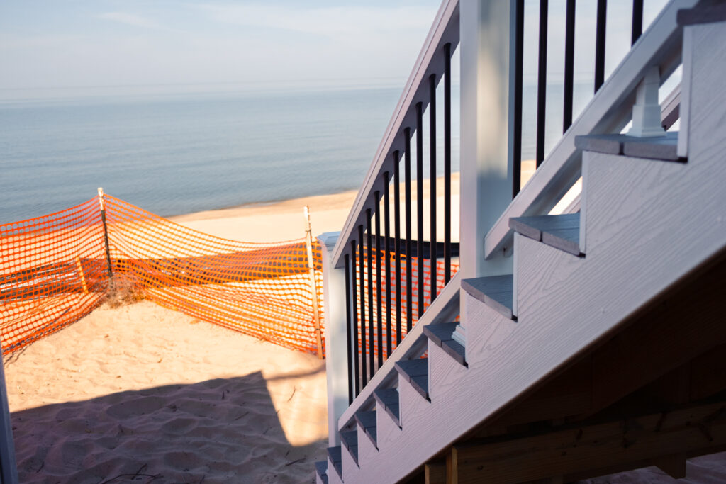 Staircase leading from deck to Lake Michigan with snow fencing up on the sand to prevent erosion control